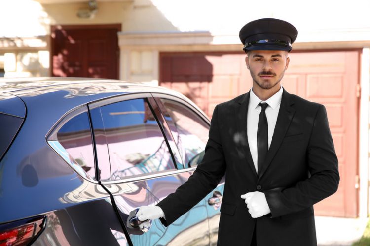 Young handsome driver standing near luxury car. Chauffeur service