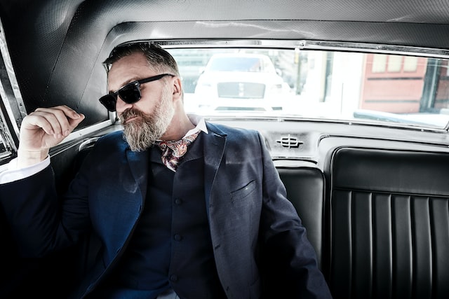 a man in a suit sits in the back seat of a car