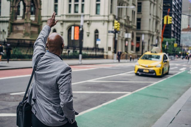 black-man-in-business-suit-catching-bright-yellow-taxi